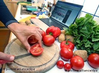 Eine Hausfrau schneidet auf einem Holzbrett Tomaten, während ein angeschalteter Laptop auf der Küchenzeile steht. Aufnahme vom 26.09.2007. Foto: Karl-Josef Hildenbrand dpa/lby +++(c) dpa - Report+++