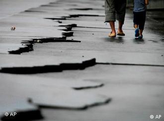 A father and son walk by cracks following a 6.5-magnitude earthquake at Yaizu port in Shizuoka Prefecture (State), Japan, Tuesday, Aug. 11, 2009. The quake hit Tokyo and nearby areas shortly after dawn Tuesday, halting trains and forcing two nuclear reactors to shut down for safety checks. (AP Photo/Itsuo Inouye)