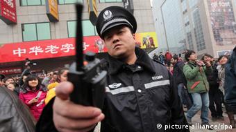 Files - A Chinese police officer disperses members of the public and media outside a McDonalds store after internet social networks called to join a 'Jasmine Revolution' protest in Wangfujing of central Beijing, China on 20 February 2011. Chinese police showed up in force to disperse a huge crowd of mostly onlookers gathered outside the fast food restaurant in Be