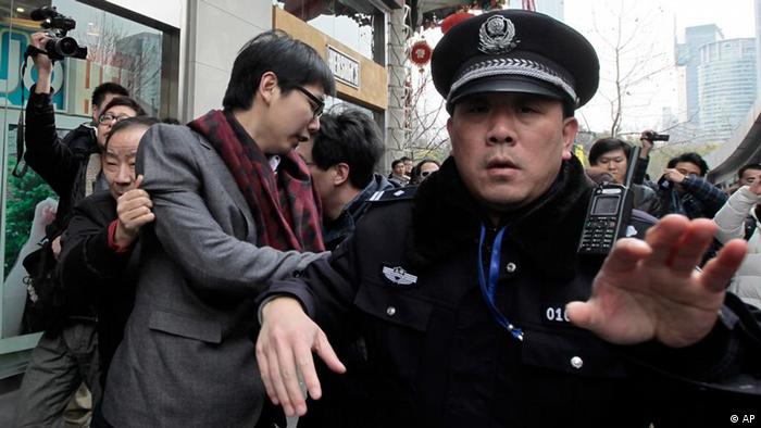 A man, 3rd from left, is detained by police officers in front of a cinema that was a planned protest site in Shanghai, China, Sunday, Feb. 20, 2011. Jittery Chinese authorities staged a show of force Sunday to squelch a mysterious online call for a "Jasmine Revolution" apparently modeled after pro-democracy demonstrations sweeping the Middle East. (AP Photo/Eugene Hoshiko)
