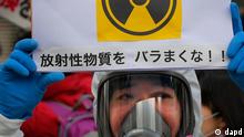 A protester in protective mask holds a placard during an anti-nuclear rally in Tokyo