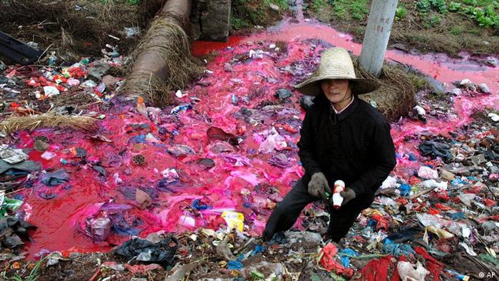 A woman collects plastic bottles near a river where water is polluted with a reddish dye directly discharged from a small paper factory nearby in Dongxiang, in east China's Jiangxi Province in this March 25, 2005 file photo. China needs to break ties between polluting industries and local officials if it is to succeed in cleaning up its badly tainted water supplies, the founder of a new environmental group said Tuesday, Sept. 18, 2006. (AP Photo, File) ** CHINA OUT **