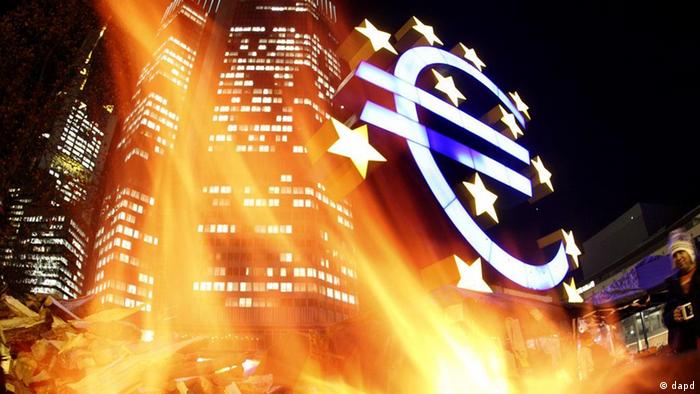 The European Central Bank in Frankfurt at night, with flames in the foreground