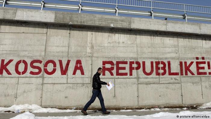 A pedestrian walks by a graffiti reading 'Kosova Republic!' in Kosovo's capital Pristina