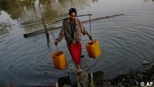 A Myanmar woman fetches water from a small pond 