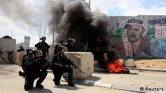 Israeli security officers take position near a burning tyre during clashes with Palestinian protesters at a demonstration marking Land Day at Qalandiya checkpoint, near the West Bank city of Ramallah, March 30, 2012. Israel shut crossings into the occupied West Bank on Friday and reinforced patrols along its borders with Lebanon and Syria to try to thwart pro-Palestinian rallies around the country. Land Day marks the annual commemorations in Israel of the killing by police of six Arab citizens in 1976 during protests against land confiscations in northern Israel's Galilee region. REUTERS/Darren Whiteside (WEST BANK - Tags: ANNIVERSARY CIVIL UNREST POLITICS TPX IMAGES OF THE DAY)