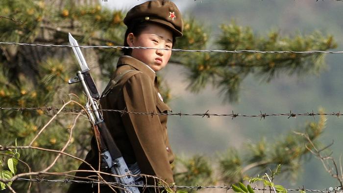In this photo taken June 3, 2009, a female North Korean soldier looks out from behind a barbed-wire fence around a camp on the North Korean river banks across from Hekou, northeastern China's Liaoning province. North Korea's top court has convicted two U.S. journalists, and sentenced them to 12 years in labor prison, the country's state news agency reported Monday. (ddp images/AP Photo/Ng Han Guan)  