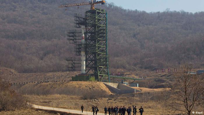 A group of journalists walk down a road in front of North Korea's Unha-3 rocket, slated for liftoff between April 12-16, at Sohae Satellite Station in Tongchang-ri, North Korea on Sunday April 8, 2012. North Korean space officials have moved a long-range rocket into position for this week's controversial satellite launch, vowing Sunday to push ahead with their plans in defiance of international warnings against violating a ban on missile activity.(Foto:David Guttenfelder/AP/dapd)
