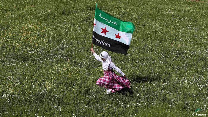 A Syrian refugee runs with a Syrian opposition flag 
