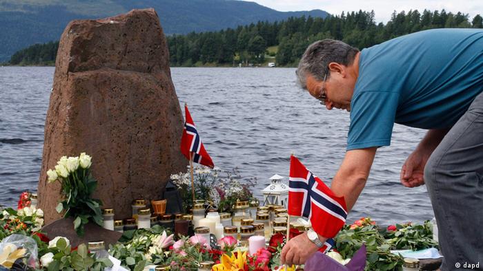 A man places a Norwegian flag between flowers to pay respect to victims of the Utoya Island massacre
