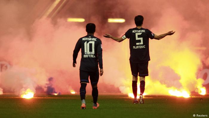 Два футболиста на фоне огня и дыма на стадионе
