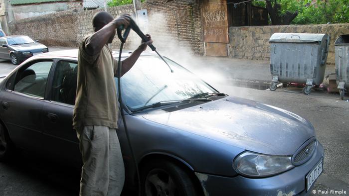 Man  sprays down a car 