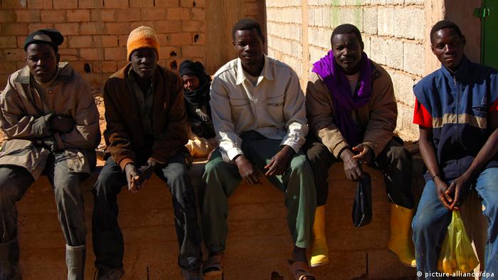 Arbeitslose afrikanische Männer sitzen auf einer Mauer, Germa, Libyen
