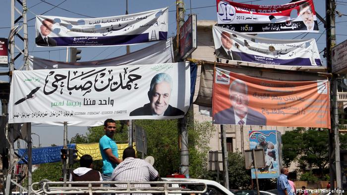 Egyptians drive under electoral billboards featuring presidential candidates in Cairo