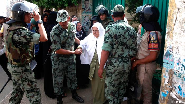 Soldiers help a woman leave a school used as a polling station in Al-Sharqya, 60 km (37 miles) northeast of Cairo, May 23, 2012. Egyptians began voting freely on Wednesday for the first time to pick their president in a wide open election that pits Islamists against men who served under deposed leader Hosni Mubarak. REUTERS/Asmaa Waguih (EGYPT - Tags: POLITICS ELECTIONS)