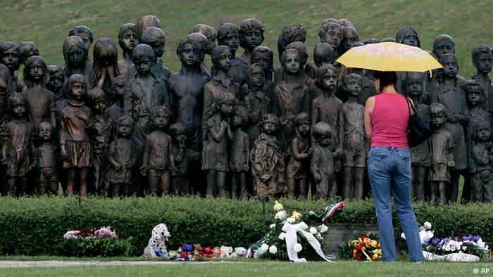 A woman stands in front of a monument in Lidice