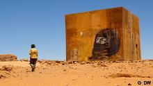 Man walking past mural outside Dajla refugee camp, western Algeria 

