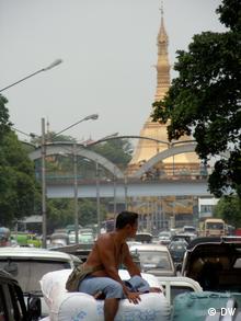 A person rides a bike on a busy street in Yangon