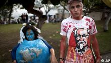 Environmental activists, one portraying a shrinking planet, left, another dressed as a butcher carrying a hatchet and donning a red-stained apron with corporate logos of fast food restaurants, attend a protest on the final day of the United Nations Conference on Sustainable Development, or Rio+20, in Rio de Janeiro, Brazil, Friday, June 22, 2012. (Foto:Felipe Dana/AP/dapd).