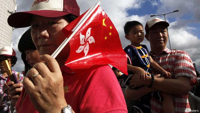A resident carrying Hong Kong and Chinese flags attends a flag-raising ceremony to mark the 15th anniversary of the territory's handover to Chinese rule, in Hong Kong July 1, 2012. REUTERS/Tyrone Siu (CHINA - Tags: POLITICS ANNIVERSARY) Eingestellt vonn Eleonore Uhlich