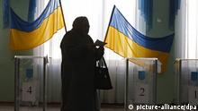 A Ukrainian woman passes in front of the voting boxes at a polling station in Kyiv, in February 2010