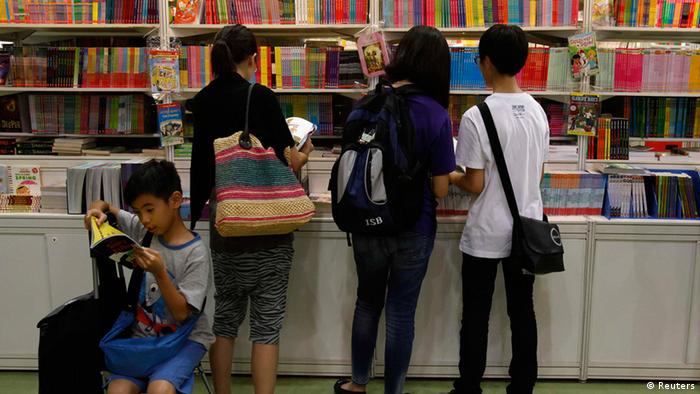 A boy reads beside parents choosing children's books inside the Hong Kong Book Fair July 18, 2012. More than 530 exhibitors from 23 countries and regions took part in the territory's biggest book fair, which opened on Tuesday through July 24. REUTERS/Bobby Yip (CHINA - Tags: MEDIA)