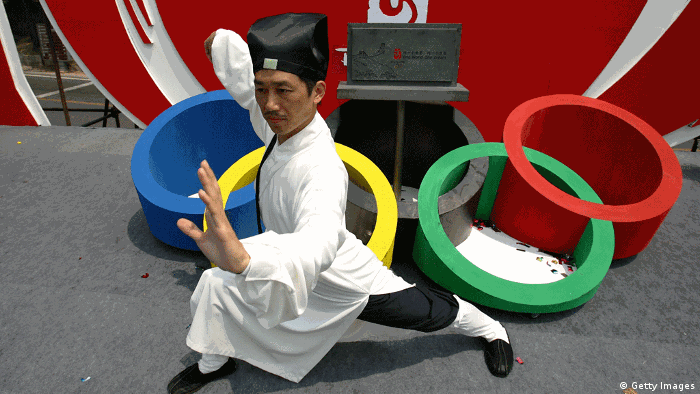 BEIJING - JUNE 23: An attendee poses for pictures in front of a table in the shape of the Olympic Rings after the opening ceremony of the fourth Olympic Cultural Festival at the Badaling section of the Great Wall on June 23, 2006 in Beijing, China. Beijing has geared up its preparation for the 2008 Games, including advancing the construction of Olympic venues, improving city facilities, launching volunteer programs and starting campaigns to boost the enthusiasm of citizens. (Photo by Cancan Chu/Getty Images) GettyImages 71281034