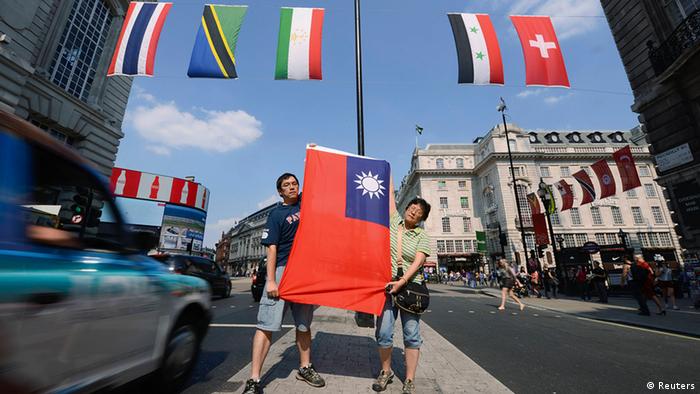 Two Taiwanese citizens hold up the flag of Taiwan (C) at the retail district of Lower Regents Street in London July 25, 2012. The International Olympic Committee decided in 1980 that Taiwan could only compete under the title Chinese Taipei and use a flag designed after the ruling.    REUTERS/ Ki Price (BRITAIN  - Tags: SPORT OLYMPICS POLITICS)