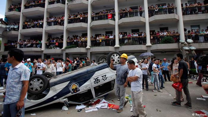 A police car lies overturned as protesters occupy a government building during a protest against an industrial waste pipeline under construction in Qidong, Jiangsu Province July 28, 2012. Angry demonstrators occupied a government office in eastern China on Saturday, destroying computers and overturning cars parked outside in a violent protest against an industrial waste pipeline they said would poison their coastal waters. The demonstration was the latest in a string of protests sparked by fears of environment degradation and highlights the social tensions the government in Beijing is having to deal with as it approaches a leadership transition this year. About a 1,000 protesters marched through the coastal city of Qidong, about one hour north of Shanghai by car, shouting slogans against the plan to build a pipeline through the city that would empty waste from a nearby paper factory into the sea. REUTERS/Carlos Barria (CHINA - Tags: ENVIRONMENT CIVIL UNREST POLITICS CRIME LAW)