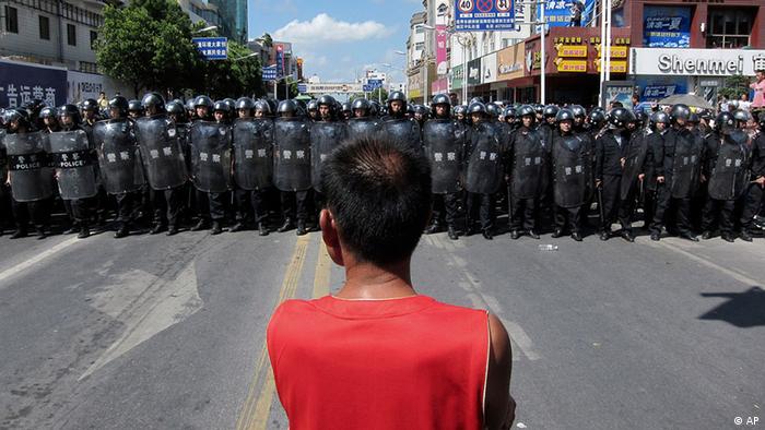 A protester stands in front of a lines of riot police officers Saturday July 28, 2012 in Qidong, Jiangsu Province, China. Authorities in eastern China dropped plans for a water-discharge project Saturday after thousands of protesters angry about pollution took to the streets, in the latest of many such confrontations in a country where three decades of rapid economic expansion have come at an environmental price. (Foto:Eugene Hoshiko/AP/dapd)
