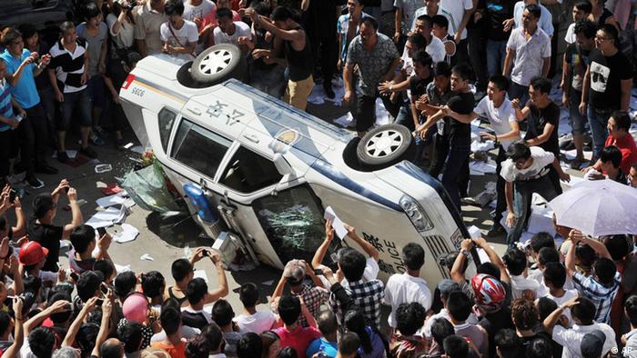 Local residents push over a police vehicle as they gather to protest against plans for a water discharge project in Qidong, China Saturday, July 28, 2012. The government in the city announced on its official website Saturday that the plans were scrapped amid opposition by local residents, who are concerned over potential pollution. (Foto:Kyodo News/AP/dapd) JAPAN OUT, MANDATORY CREDIT, NO LICENSING IN CHINA, HONG KONG, JAPAN, SOUTH KOREA AND FRANCE


