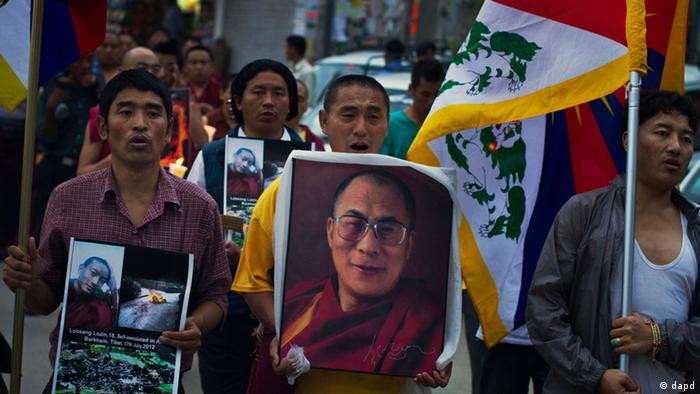 Tibetan exiles carry Tibetan flags and a portrait of the spiritual leader Dalai Lama, center, during a candlelit vigil in Dharmsala, India, Tuesday, July 17, 2012 to express solidarity with Lobsang Lozin, an 18-year-old Tibetan monk whom they say died of self-immolation in southwestern China's Sichuan province. The International Campaign for Tibet says 42 Tibetans have self-immolated since March 2011. Activists say the self-immolations are in protest of Beijing's heavy-handed rule in the region. The Chinese government has confirmed some but not all of the deaths by self-immolation. (AP Photo/ Ashwini Bhatia)