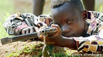 Um soldado de 10 anos de idade, da milícia armada União dos Patriotas Congoleses, em treinamento no ano de 2003, nas proximidades de Bunia no Congo