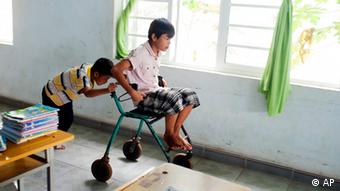 A Vietnamese boy pushes another boy in a wheelchair
