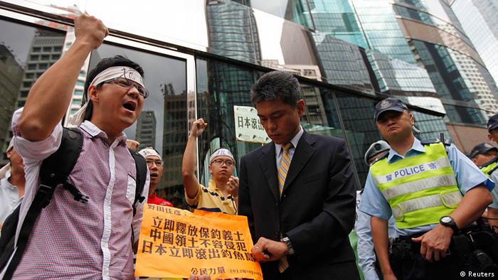 Protesters chant slogans as a representative from the Japanese Consulate (C) prepares to receive a petition letter demanding the release of detained activists after they landed on disputed islands, called Senkaku in Japan, and Diaoyu in China, in Hong Kong August 16, 2012. Japan is considering deporting 14 Chinese activists arrested over their landing on a disputed island as soon as Friday in a move that could defuse a worsening feud between Tokyo and Beijing, Japanese media reported on Thursday. The activists, seven of whom landed on Wednesday on the rocky, uninhabited isle in the East China Sea claimed by both nations, have been transferred to Okinawa for questioning by police on Thursday morning, public broadcaster NHK said. The sign reads, "Release of detained activists. Sovereignty of Diaoyu Islands cannot be invaded. Japan get out from Diaoyu islands" REUTERS/Tyrone Siu (CHINA - Tags: POLITICS CIVIL UNREST CRIME LAW)