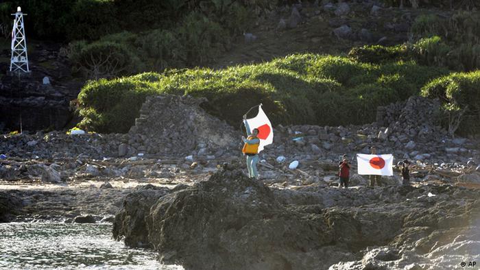 Japanese activists hold the national flags on Uotsuri island, one of the islands of Senkaku in Japanese and Diaoyu in Chinese, in East China Sea, Sunday, Aug. 19, 2012. Japan’s Coast Guard says a group of Japanese activists have landed on Uotsuri, one of a group of islands at the center of an escalating territorial dispute with China. (Foto:Kyodo News/AP/dapd) JAPAN OUT, MANDATORY CREDIT, NO LICENSING IN CHINA, HONG KONG, JAPAN, SOUTH KOREA AND FRANCE