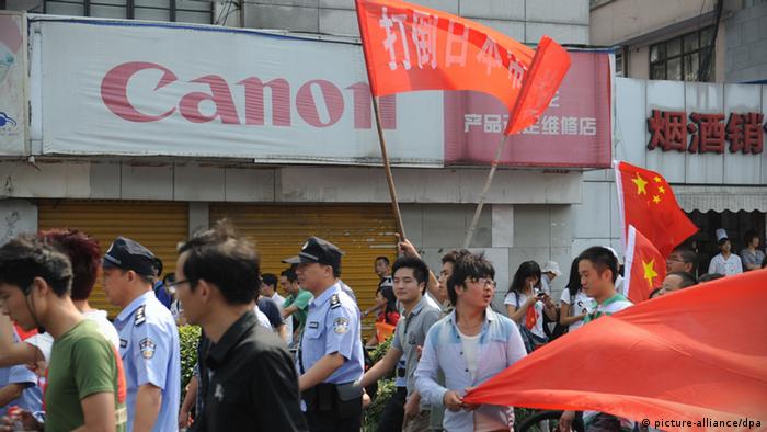 People in an anti-Japan protest pass by a closed shop of Canon products in Hangzhou in east China's Zhejiang province Sunday Sept. 16, 2012. Japan has urged China to ensure the safety of Japanese citizens and businesses in China after violence aiming at Japanese businesses and products are reported in the protests on Saturday. Photo via Newscom picture alliance
