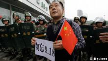 A protester holds a Chinese national flag and a paper bearing slogan as he stands in front of paramilitary policemen on the 81st anniversary of Japan's invasion of China, in Chengdu, Sichuan province, September 18, 2012. Hundreds of Japanese businesses and the country's embassy suspended services in China on Tuesday, expecting further escalation in violent protests over a territorial dispute between Asia's two biggest economies. Chinese characters on the paper read "Do not forget 9.18." REUTERS/Jason Lee (CHINA - Tags: POLITICS CIVIL UNREST ANNIVERSARY)