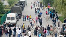 Workers walk past several paramilitary police vehicles near an entrance of a Foxconn Tech-Industry Park as onlookers watch from the outside in Taiyuan, Shanxi province, September 24, 2012. Taiwan's Foxconn Technology Group closed its Taiyuan plant in northern China on Monday after a personal dispute spiraled into a brawl involving 2,000 workers in a dormitory late on Sunday night, injuring 40. The Taiyuan plant makes automobile electronic components, consumer electronic components and precision moldings. REUTERS/Stringer (CHINA - Tags: BUSINESS CIVIL UNREST SCIENCE TECHNOLOGY EMPLOYMENT) CHINA OUT. NO COMMERCIAL OR EDITORIAL SALES IN CHINA