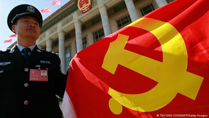 A Chinese policeman holds a Chinese Communist Party flag to show his supports to the party during the 17th Communist Party Congress in Beijing 15 October 2007. Chinese President Hu Jintao ended a long speech on 15 October outlining the Communist Party's performance and its major priorities for the economy, environment, military, Taiwan and social issues. AFP PHOTO/TEH ENG KOON (Photo credit should read TEH ENG KOON/AFP/Getty Images) 