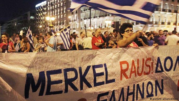 A demonstrator holds a banner that reads 'Merkel Raus!' (Merkel Out!) (picture: EPA/ORESTIS PANAGIOTOU/dpa)



