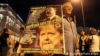 epa03425966 A demonstrator holds a poster depicting Adolf Hitler and German Chancellor Angela Merkel during a protest in front of the Parliament building against new austerity measures in Athens, Greece, 08 October 2012. The protest, called by trade unions, took place one day ahead the visit of German Chancellor Angela Merkel in Athens. The banner reads 'Dont buy German products, Resistance against fourth Reich'. EPA/ORESTIS PANAGIOTOU +++(c) dpa - Bildfunk+++
