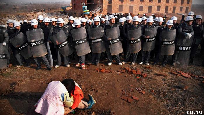 A woman is warded off by policemen as she tries to stop the demolition of a house built illegally on public land in Zuoling, Hubei province, in this December 17, 2009 file photo. Forced evictions in China, a major source of social discontent, have risen significantly in the past two years as local officials and property developers colluded to seize and sell land to pay off government debt, Amnesty International said on October 11, 2012. The demolition was to make way for a railway project, local media said. REUTERS/Stringer (CHINA - Tags: POLITICS MILITARY BUSINESS REAL ESTATE CIVIL UNREST) CHINA OUT. NO COMMERCIAL OR EDITORIAL SALES IN CHINA
