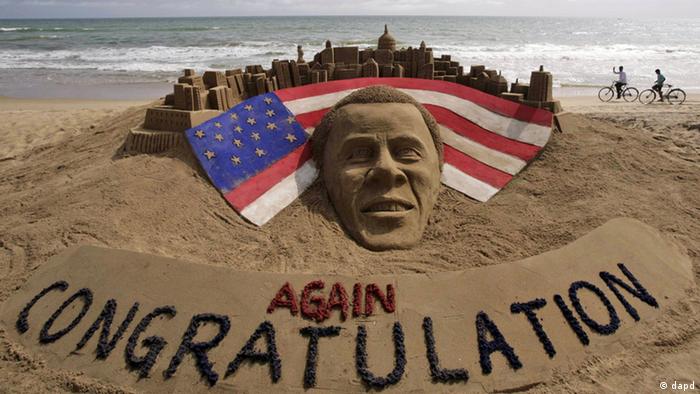 Cyclists ride on a beach passing by a sand sculpture congratulating U.S. president Barack Obama for a second term in office in Puri, India, Wednesday, Nov. 7, 2012. Obama captured a second White House term, blunting a mighty challenge by Republican Mitt Romney as Americans voted for a leader they knew over a wealthy businessman they did not. (Foto:Biswaranjan Rout/AP/dapd)
