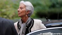 A gray-haired woman wearing a white blazer and a black and white scarf steps out of a black automobile
(Photo: EPA/OLIVIER HOSLET)
