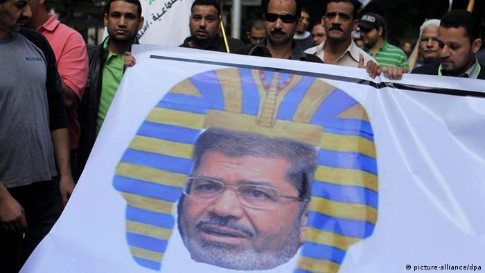 epa03483533 Egyptian protesters hold a banner depicting Egyptian President Morsi as a Pharaoh, during a rally over Morsi decrees, in Garden City, Cairo, Egypt, 23 November 2012. Opposition planned a mass rally to protest constitutional changes ordered by the Islamist President Morsi. Morsi on 22 November signed constitutional amendments making his decisions immune to judicial review. EPA/ANDRE PAIN
