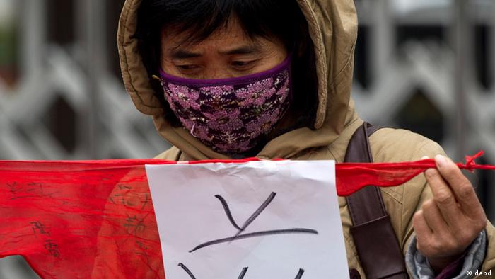 A woman displays a red scarf with a piece of paper with a Chinese character meaning HIV during a protest outside the Ministry of Civil Affairs in Beijing, China, Thursday, Nov. 24, 2011. About 30 petitioners who they said were infected with HIV from blood transfusions held up a chain of red scarves to symbolize their demands the government to provide compensation for their children's treatment, in conjunction of the upcoming World AIDS Day, which falls on Dec. 1. (AP Photo/Andy Wong)