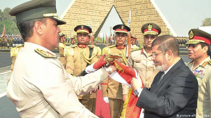 epa03421199 A handout photo released by the Egyptian Presidency shows Egyptian President Mohamed Morsi (2-R) kissing the national flag next to Minister of Defence Abdel Fattah al-Sisi (R) during Morsi's visit to former Egyptian President Anwar al-Sadat's tomb in Cairo, Egypt, 04 October 2012. EPA/EGYPTIAN PRESIDENCY HANDOUT HANDOUT EDITORIAL USE ONLY/NO SALES +++(c) dpa - Bildfunk+++
