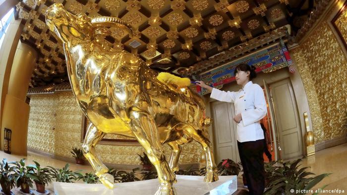 A staff polishes a gold ox statue using a ton of pure gold in Longxi International Hotel in Huaxi Village, Jiangyin, east Chinas Jiangsu Province, 6 October 2011. Huaxi village in east Chinas Jiangsu Province grabbed attention after completing a 328-meter high building that houses a statue of an ox made from a ton of gold. The village which has been dubbed as Chinas richest village spent more than 3 billion yuan (about 0.46 billion U.S. dollars) to build the 74-story building. The building opened as a hotel, named Longxi International Hotel, on October 8th to celebrate the 50th anniversary of the villages founding. Photo Yang Kejia