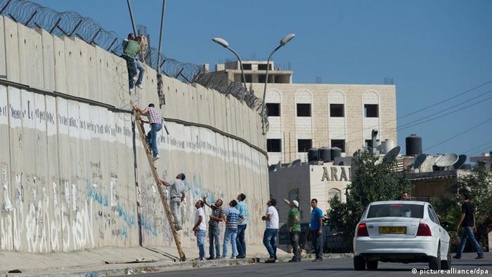 Palestinians mens use a ladder to cross over a separate wall 
Picture by Johanna Geron 